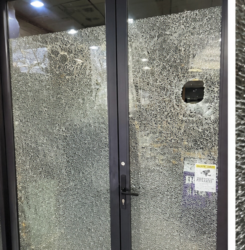 Shattered shopfront door glass awaiting emergency glazing