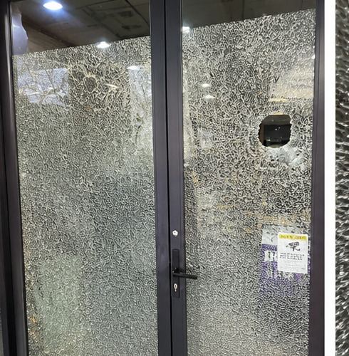 Shattered shopfront door glass awaiting emergency glazing