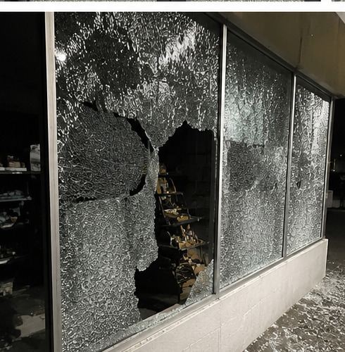 Broken shop window with glass on pavement